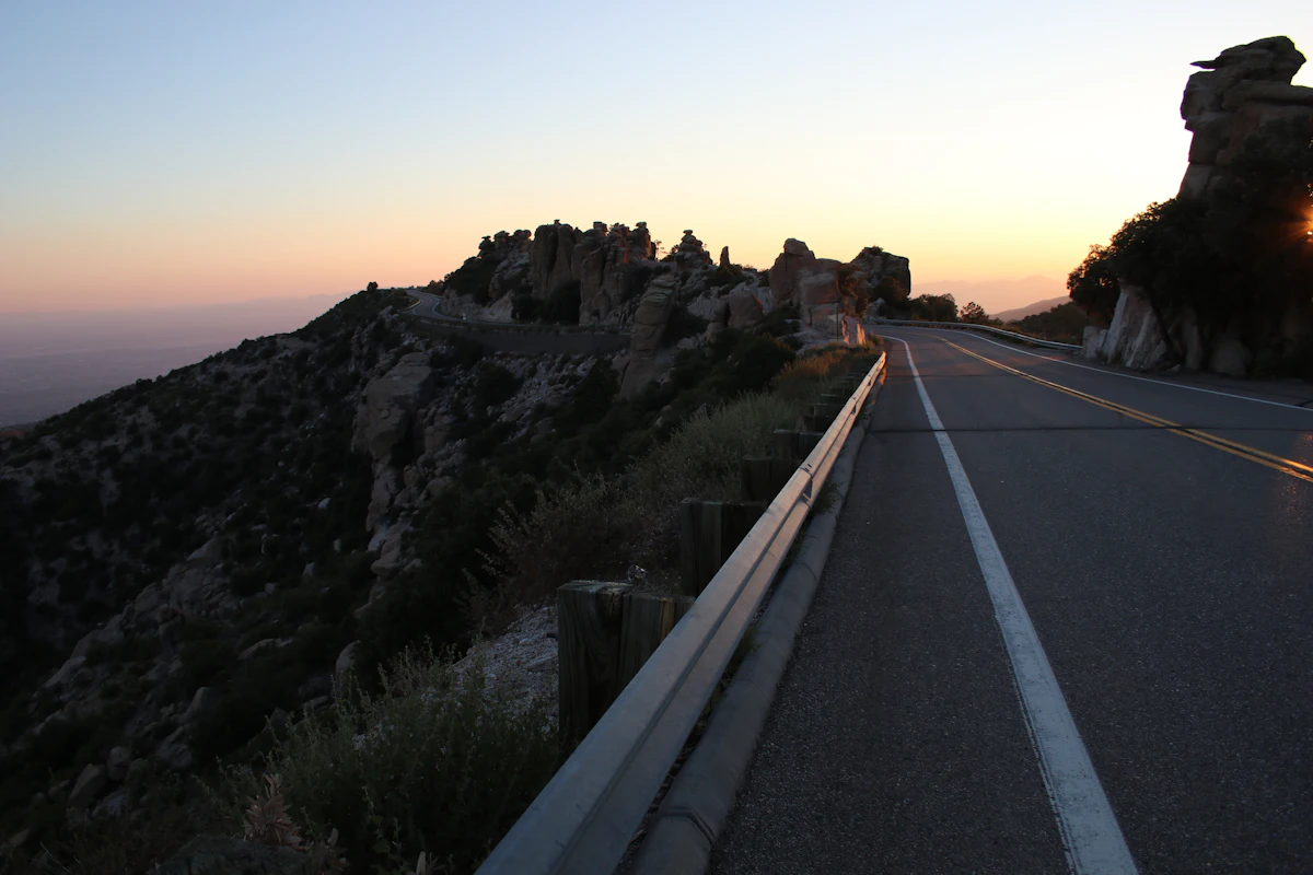 A paved mountain road with a guardrail, winding past rock outcrops near Tucson