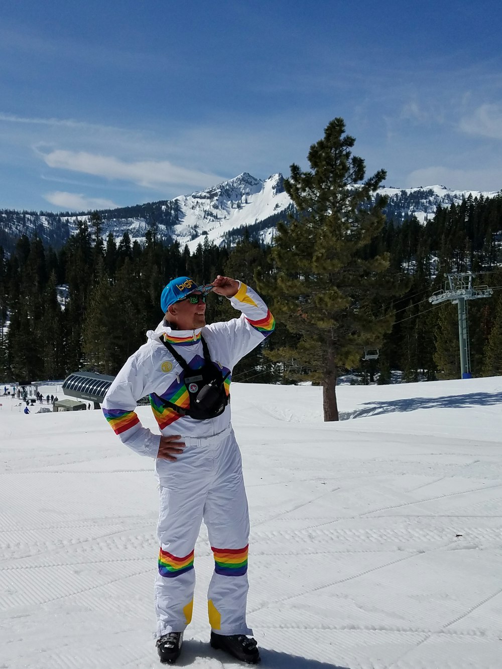 man in white and green jacket and pants standing on snow covered ground during daytime