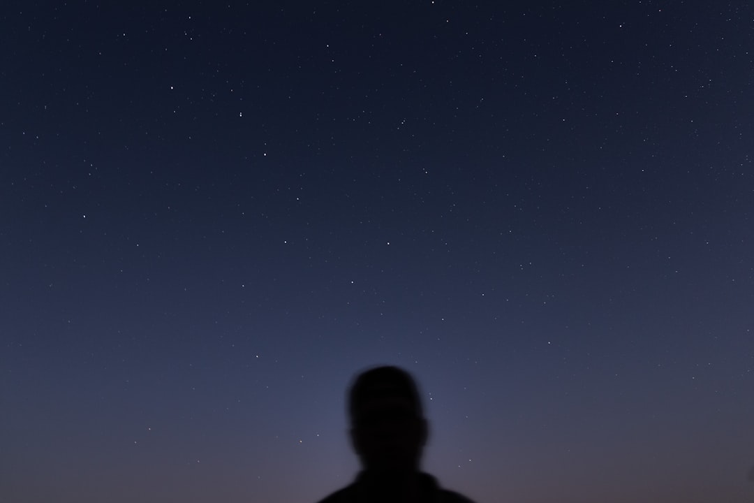 man in black jacket standing under blue sky during night time