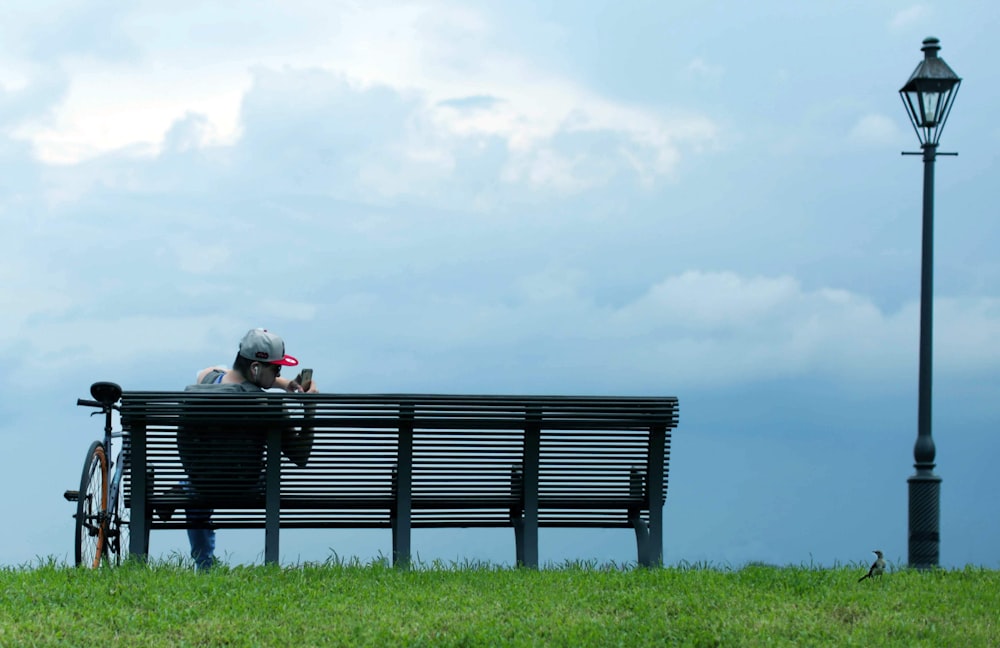 man and woman sitting on black wooden bench on green grass field during daytime