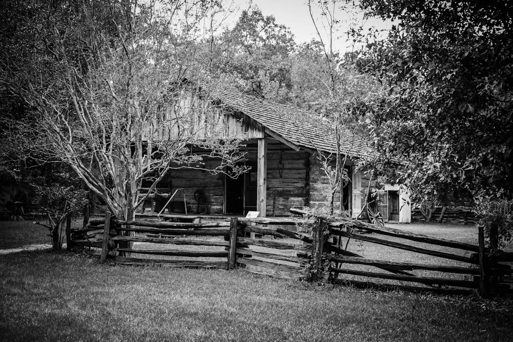 grayscale photo of wooden house near trees