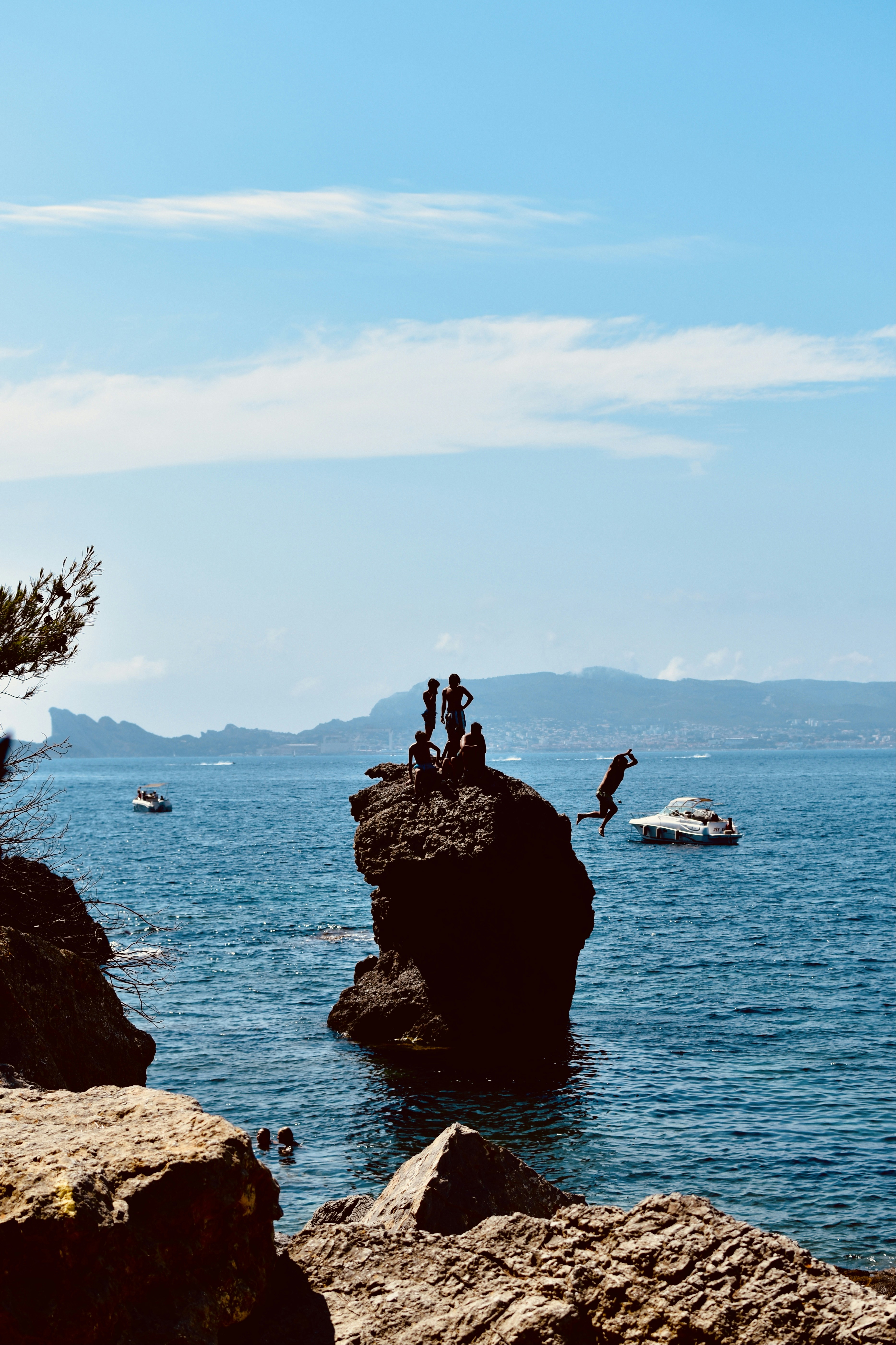 2 person standing on rock formation near body of water during daytime