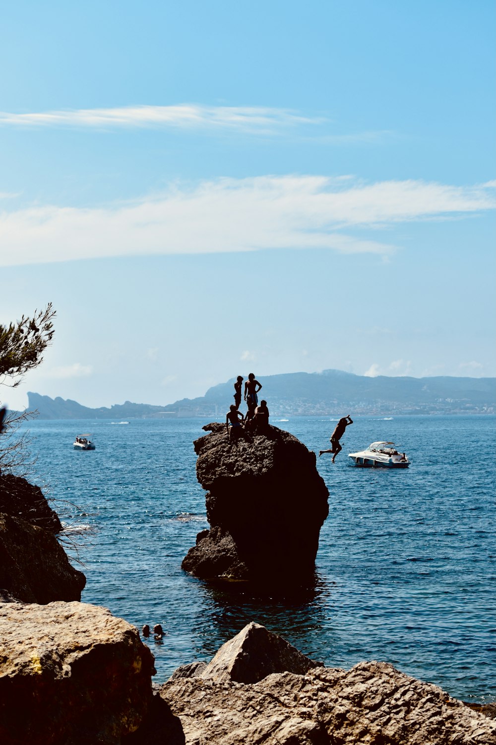 2 person standing on rock formation near body of water during daytime