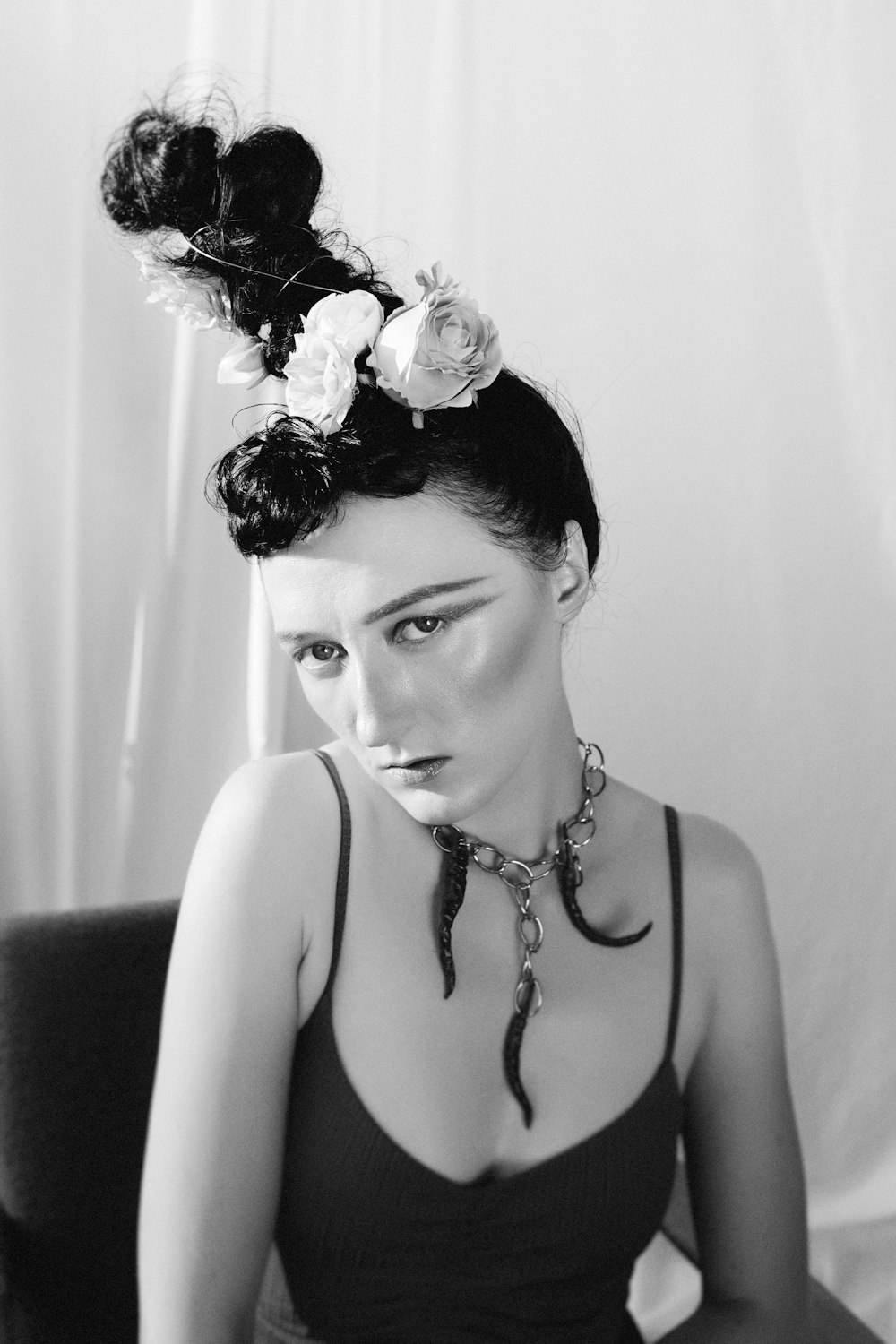 donna in canotta nera con fiore bianco sull'orecchio