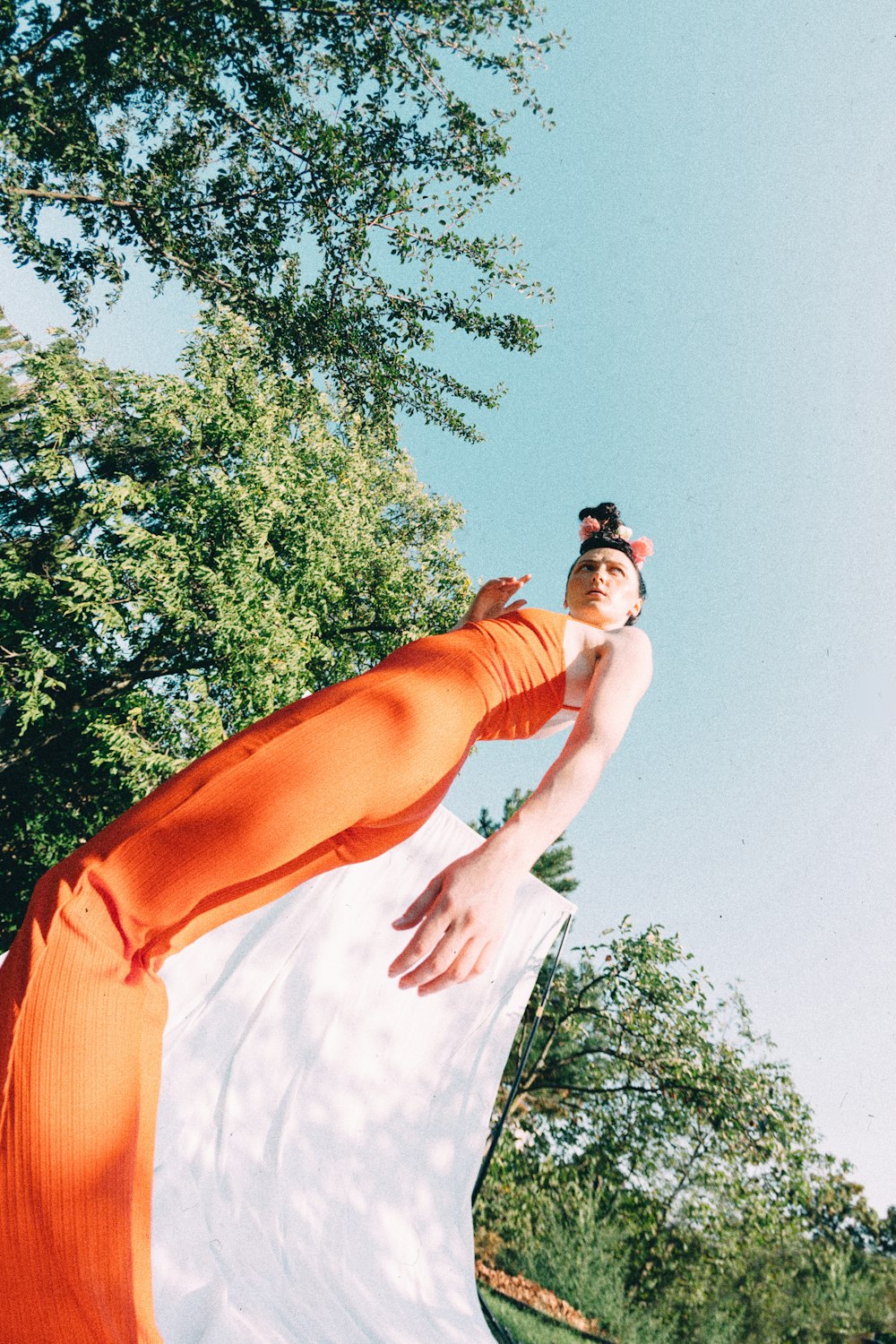 woman in orange dress standing under green tree during daytime