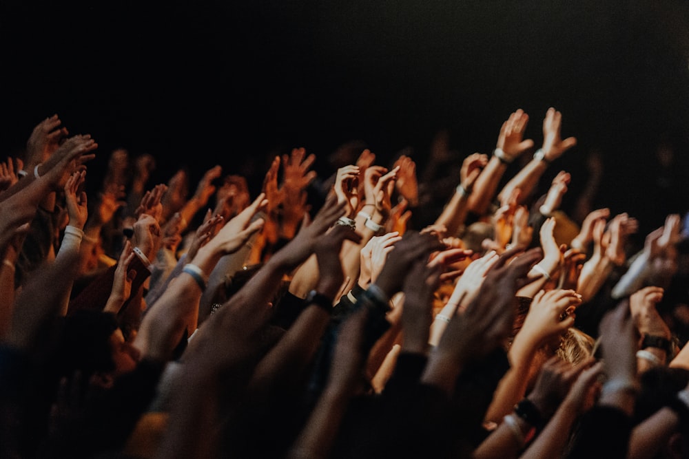 a crowd of people raising their hands in the air