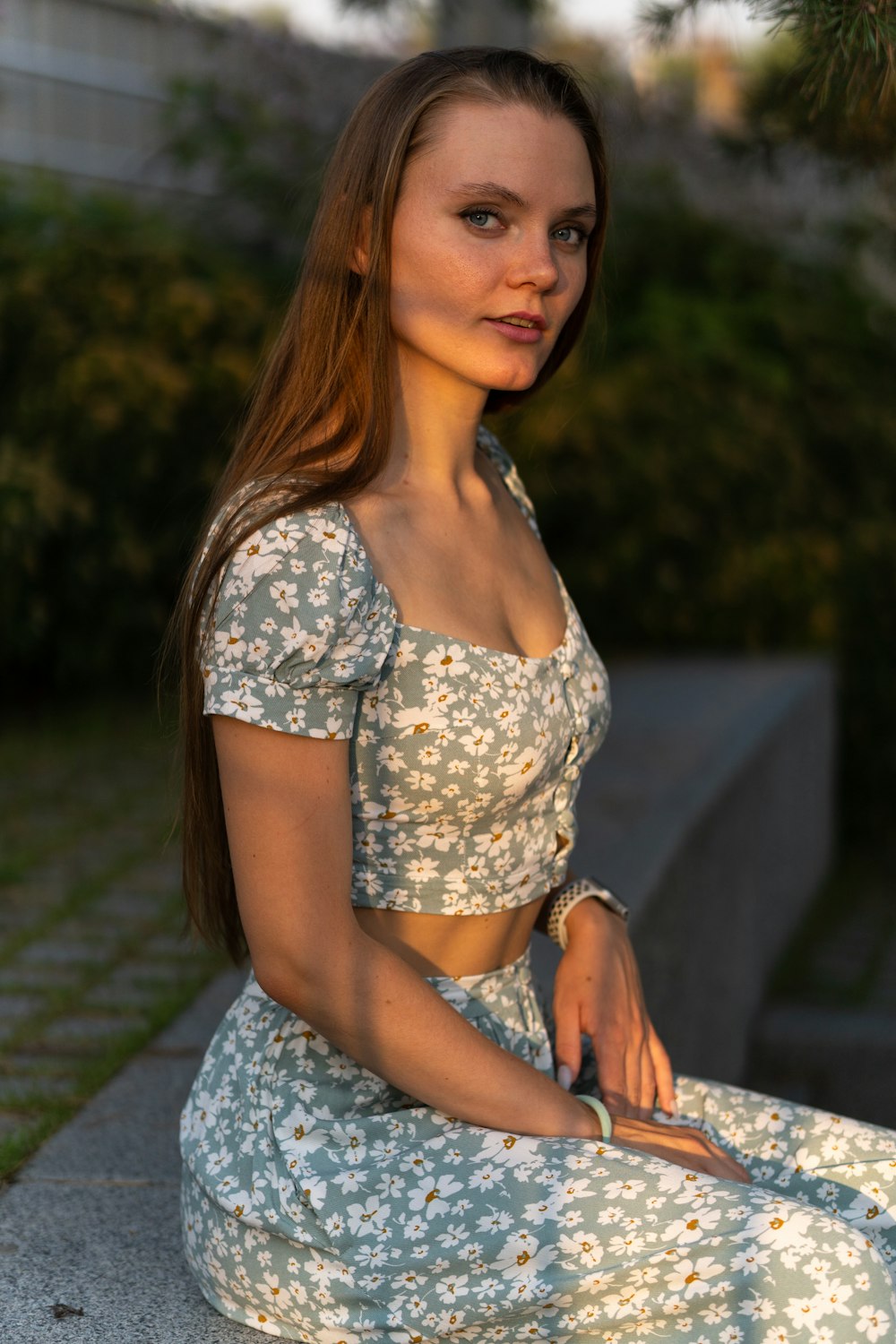 woman in white and blue floral dress sitting on gray concrete bench