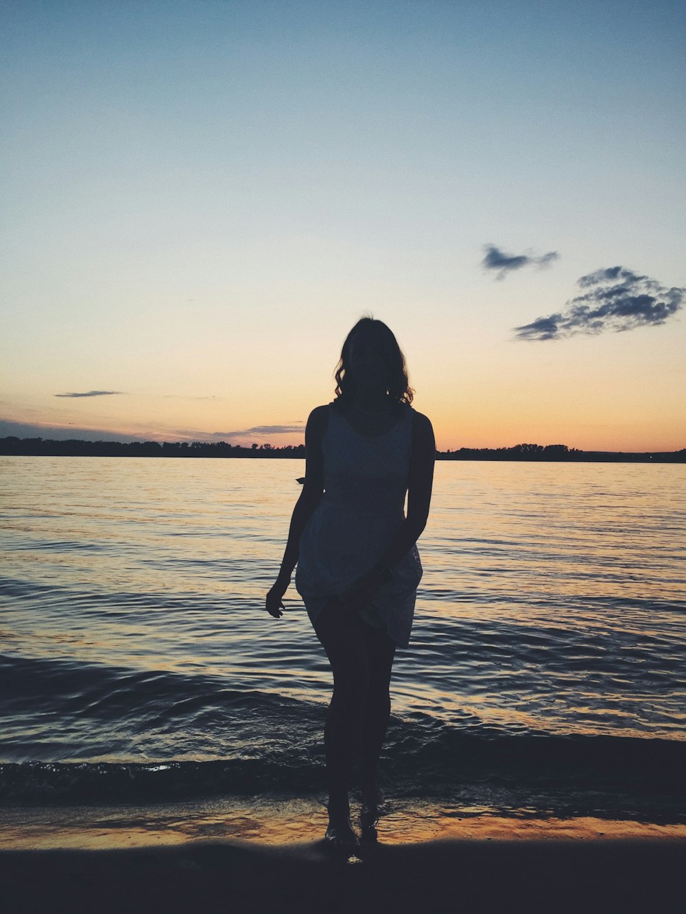 woman in black tank top standing on beach during sunset