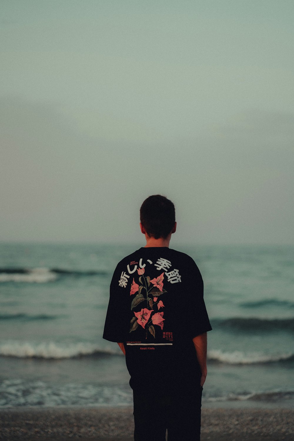 homme en noir et rouge ras du cou T-shirt debout sur le bord de mer pendant la journée