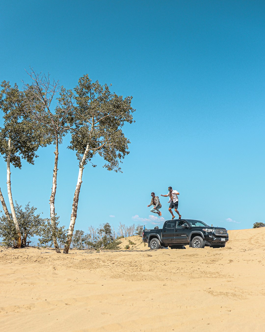 man in black t-shirt sitting on black car during daytime