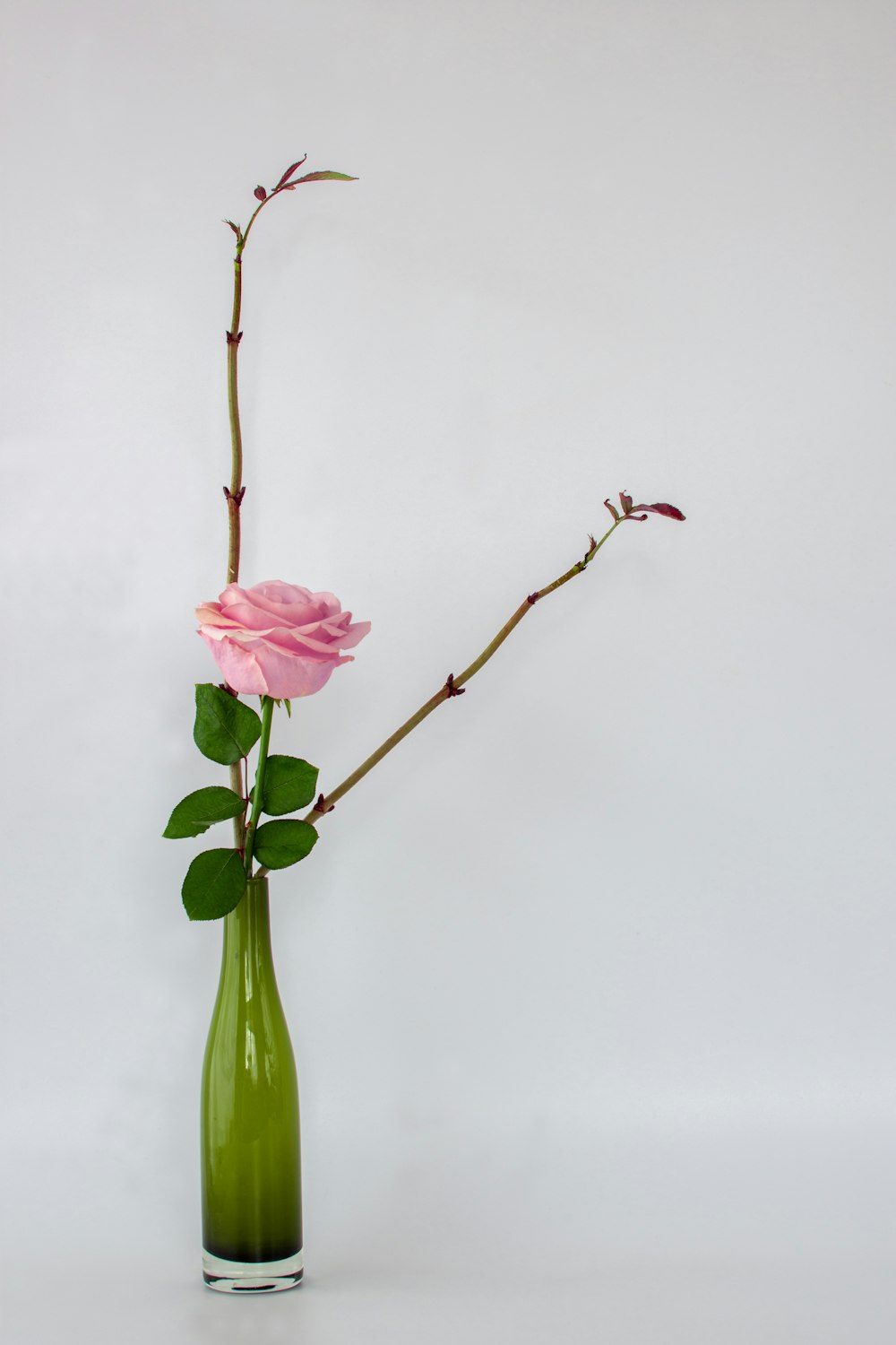 pink flower in green glass vase