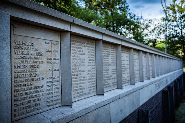 A solemn memorial wall engraved with names of fallen American service members under a clear blue sky.