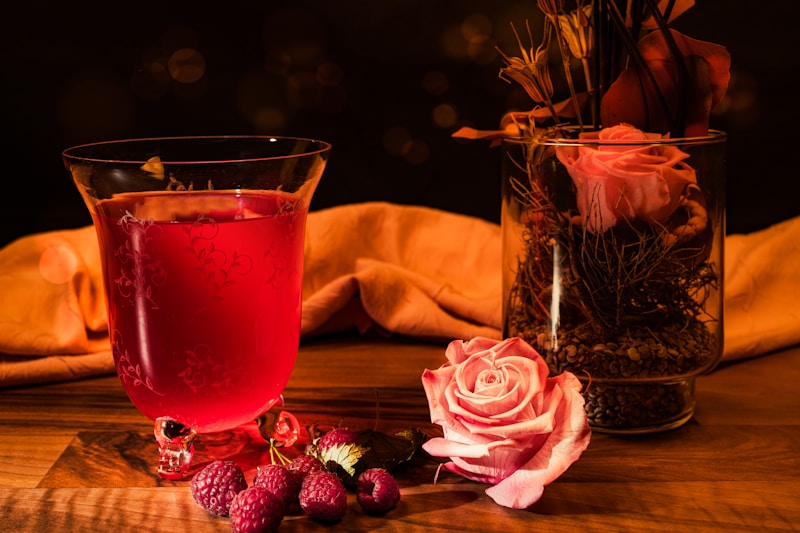 Food photography raspberry with raspberry drink photographed on a dark background with bouquet of flowers.