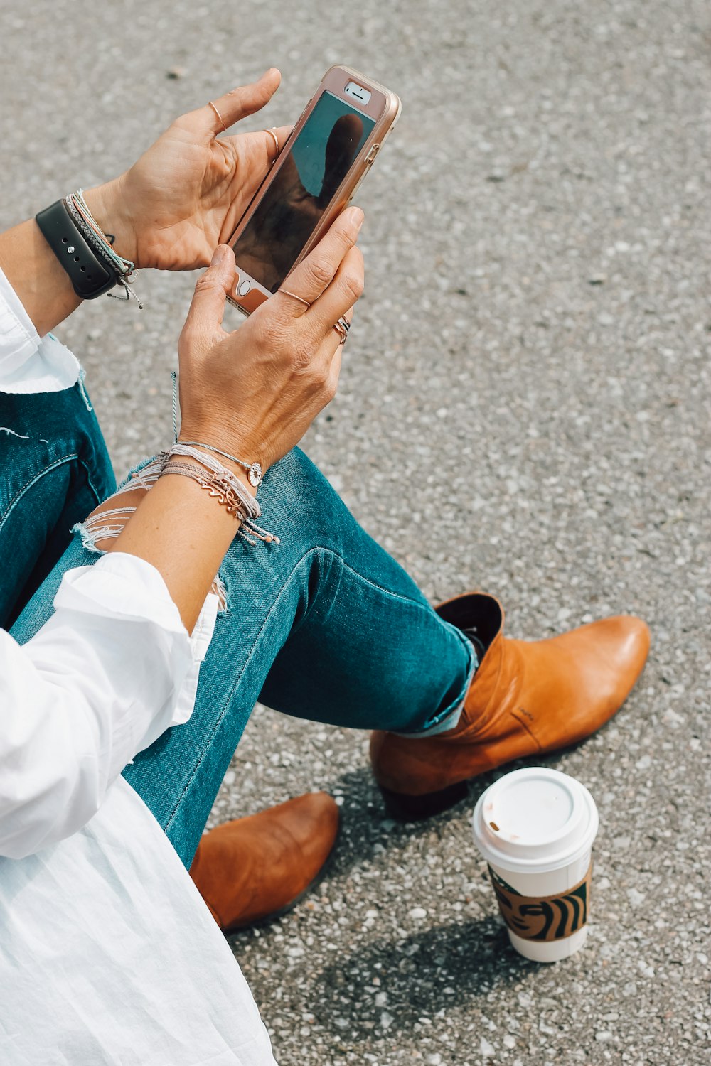 person in blue denim jeans and brown leather boots sitting on concrete floor