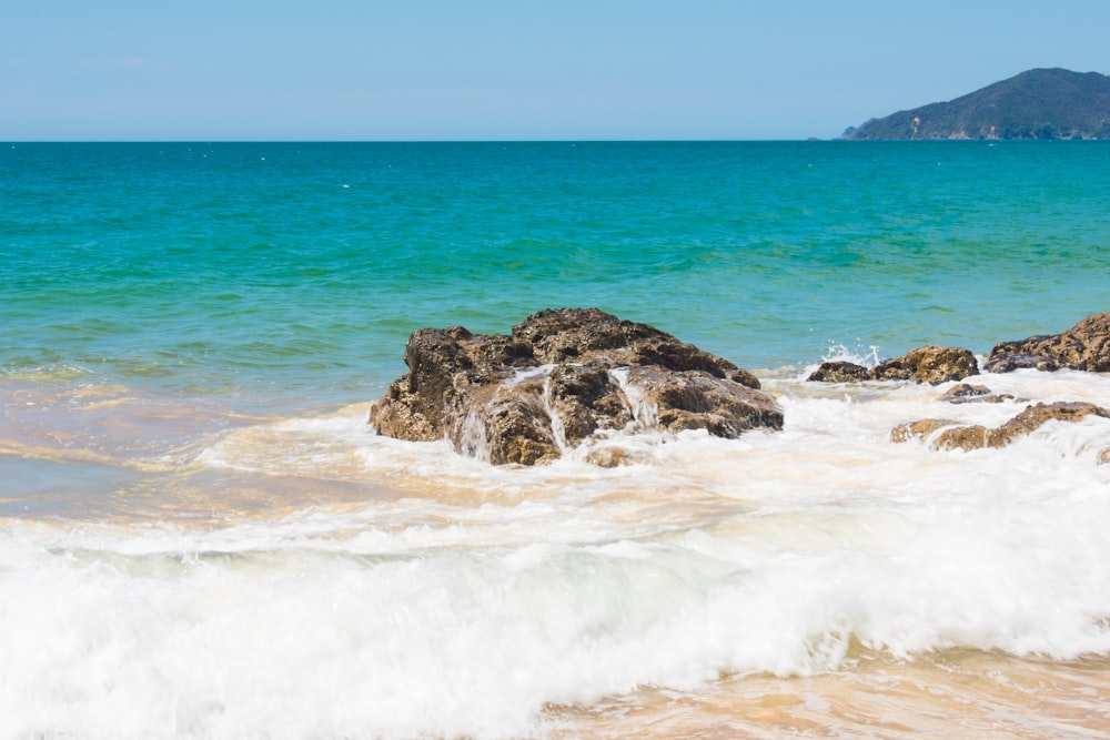 ocean waves crashing on brown rock formation during daytime