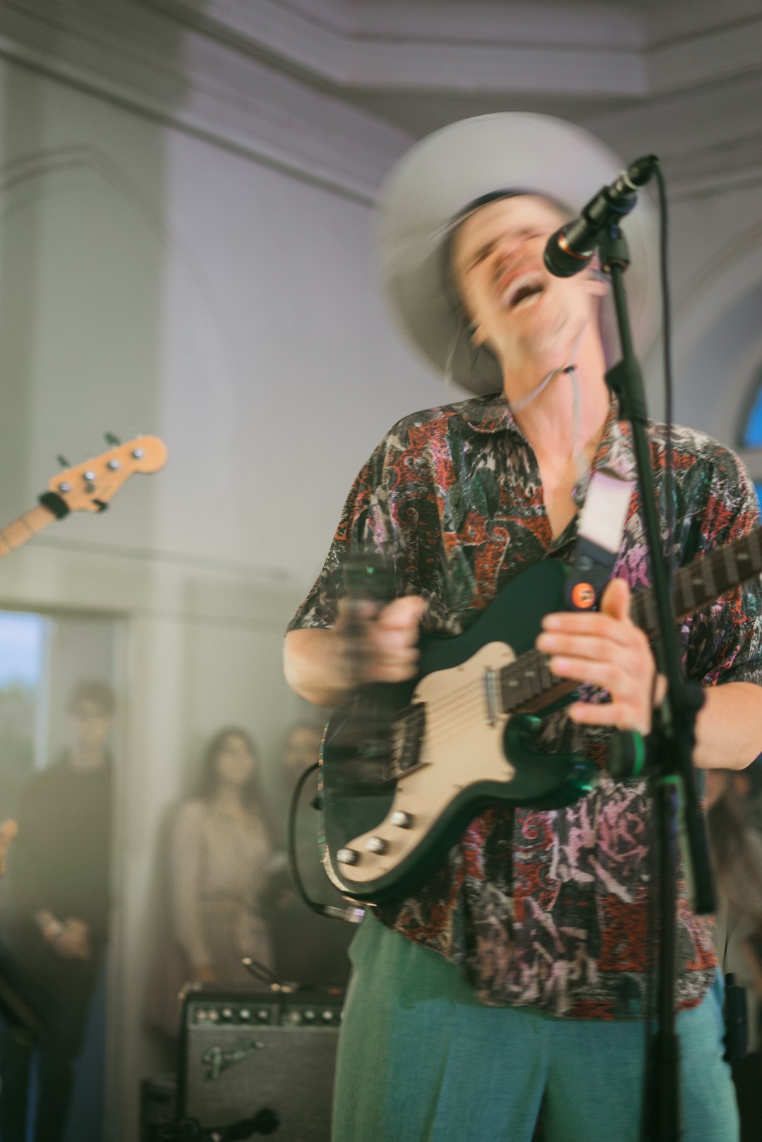 man in red and black floral button up shirt playing electric guitar