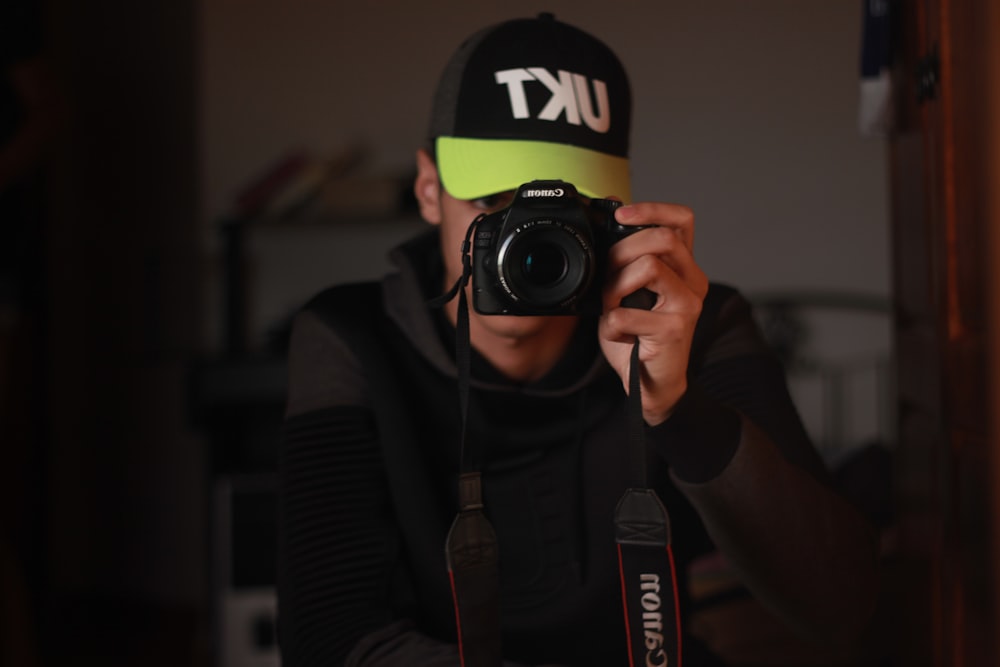 man in black and yellow nike hoodie wearing black and green nike cap