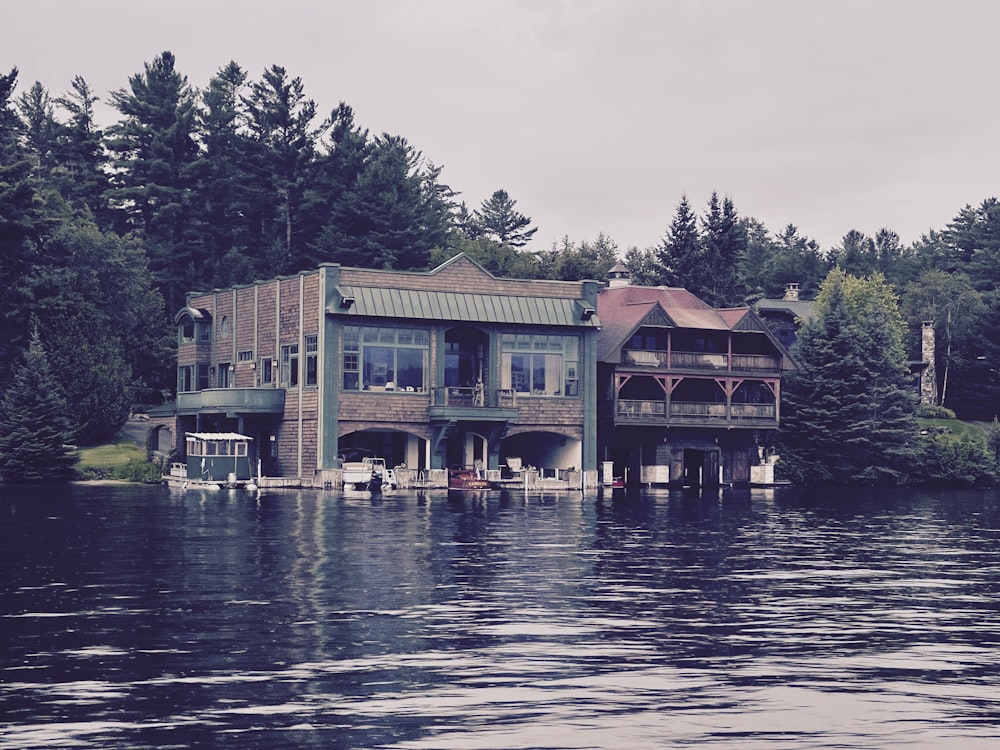 green and brown wooden house near body of water during daytime