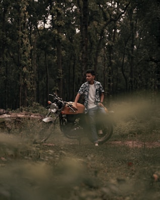Gul Tariq posing with her motorcycle in a forest.