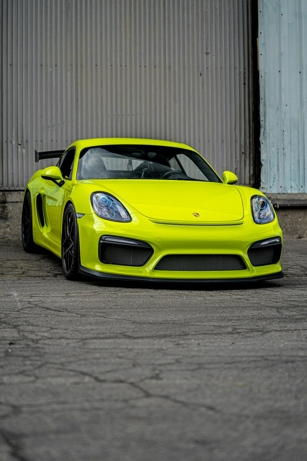 yellow porsche 911 parked near white wall