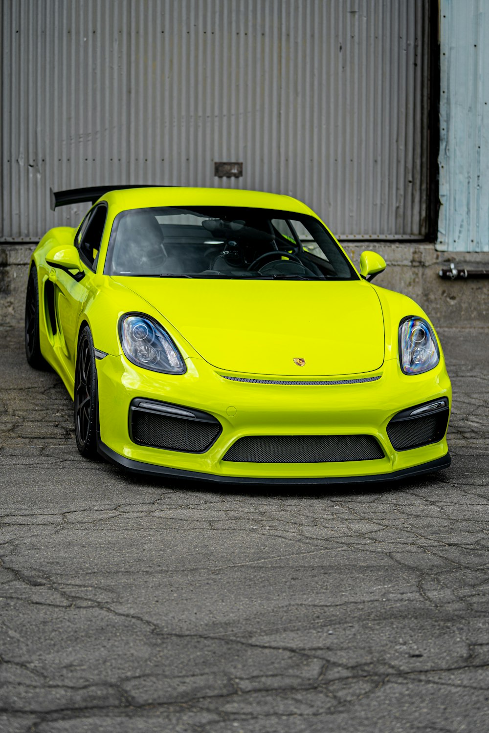 yellow porsche 911 parked near white building