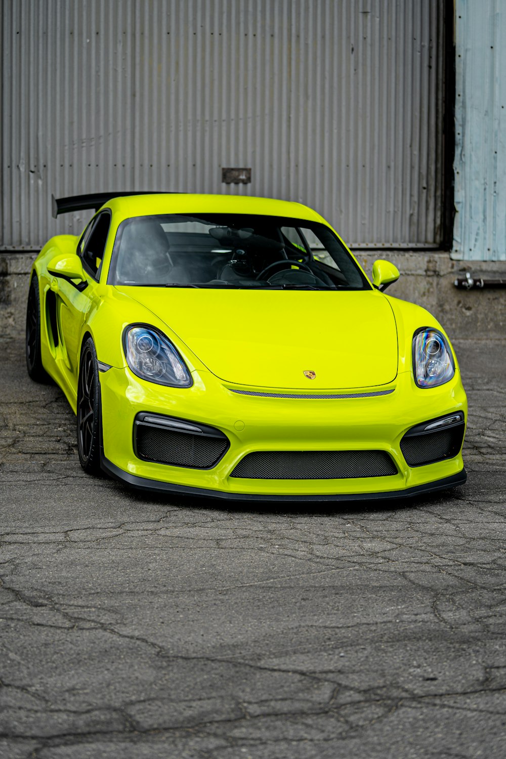 Porsche 911 amarillo aparcado cerca de un edificio blanco