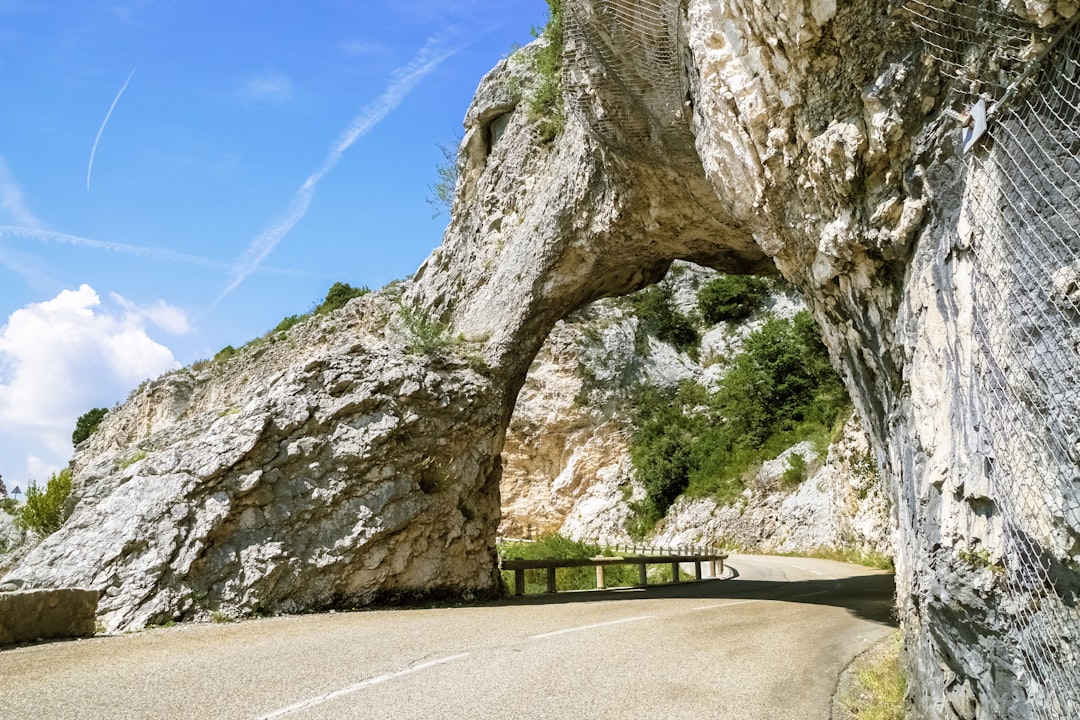 gray concrete road between gray rock formation under blue sky during daytime