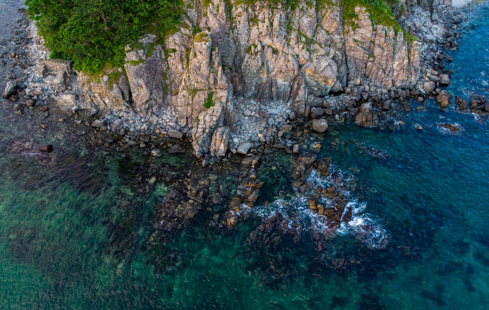 Montagne Rocheuse brune et verte à côté d’un plan d’eau pendant la journée