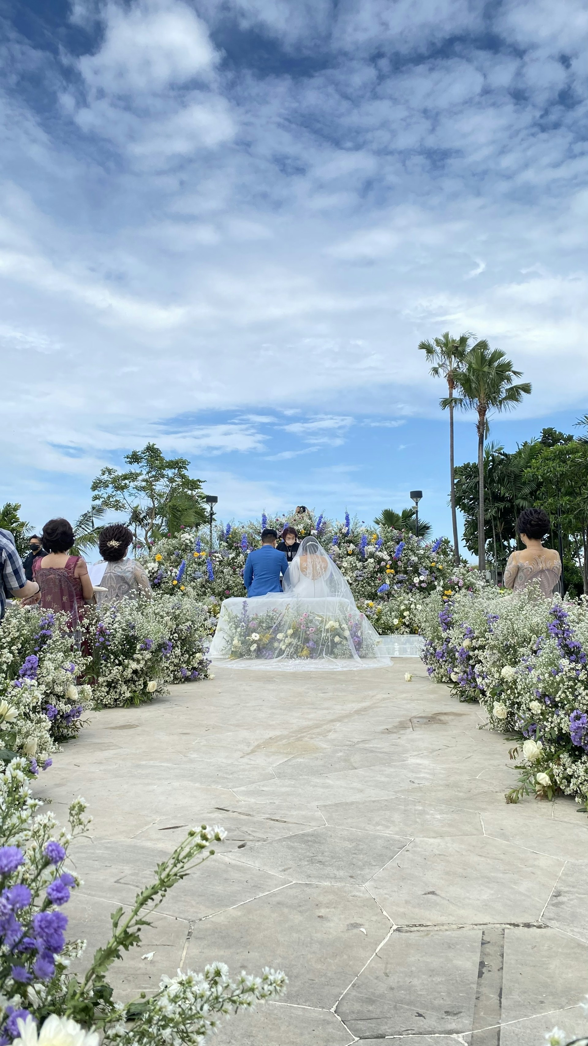 A serene outdoor wedding scene with a couple exchanging vows under a floral arch.