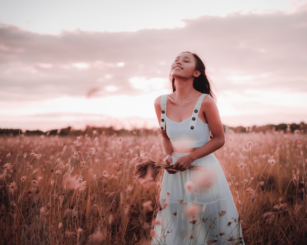 woman in white tank dress standing on brown grass field during daytime