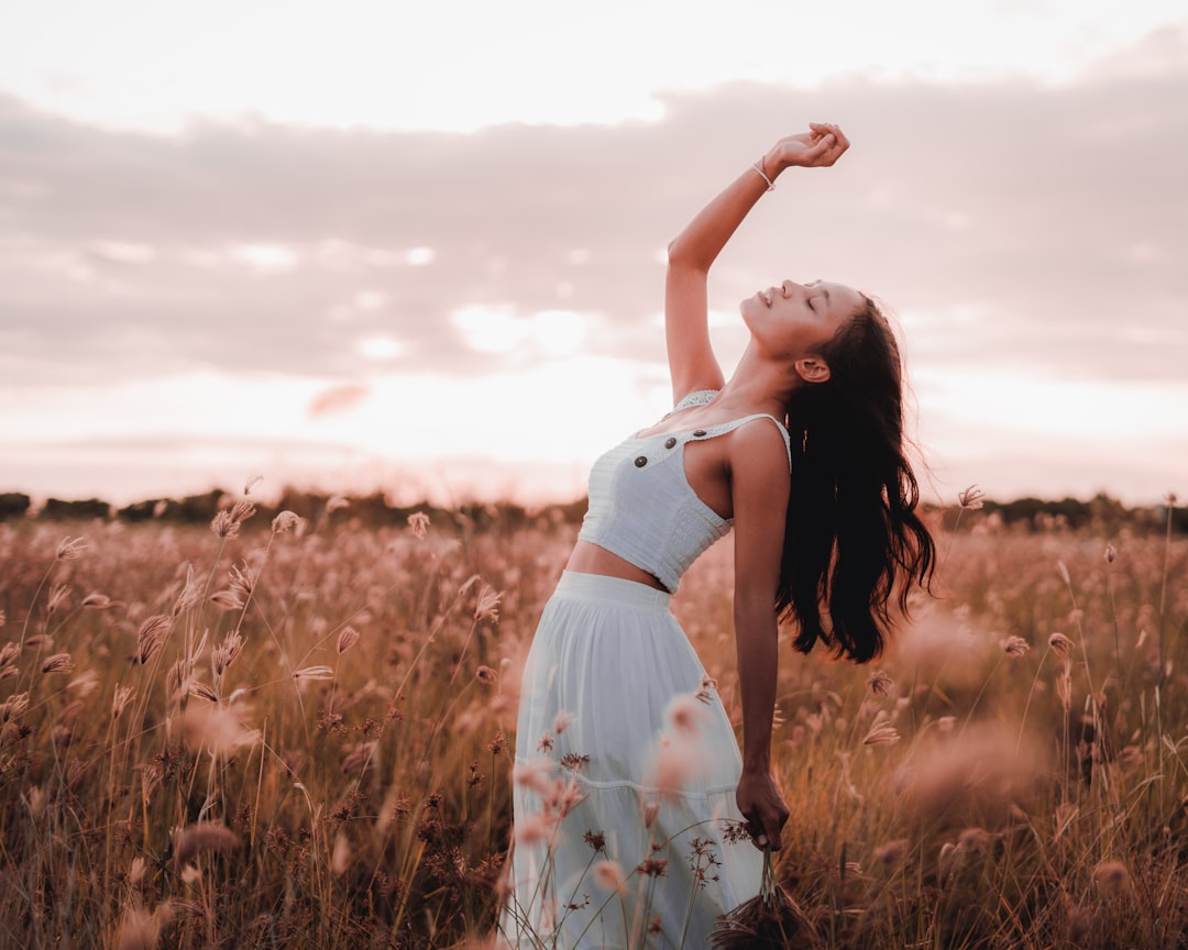 woman in white and red floral dress standing on brown grass field during daytime