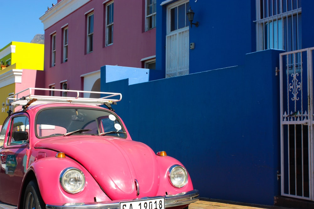 red and white vintage car parked beside blue building
