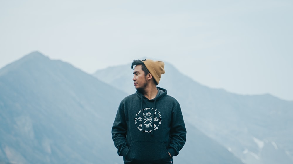 man in black and white sweater standing on top of mountain during daytime