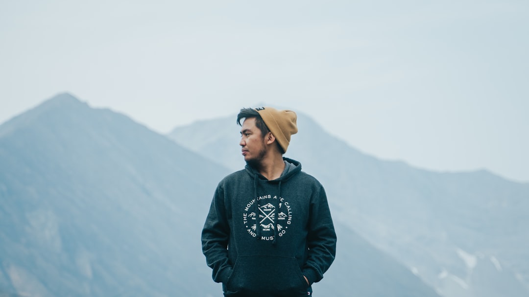 man in black and white sweater standing on top of mountain during daytime