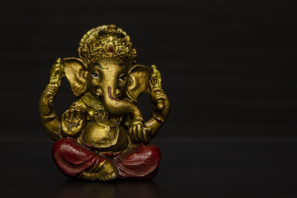 gold hindu deity figurine on black surface