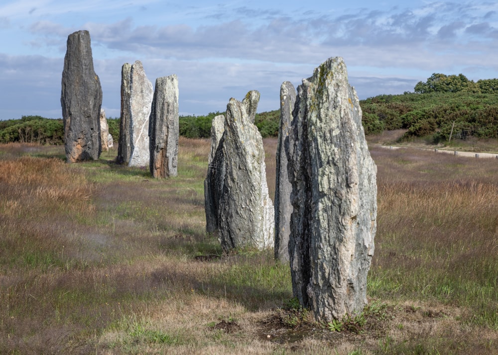 gray rock formation on green grass field under white clouds during daytime