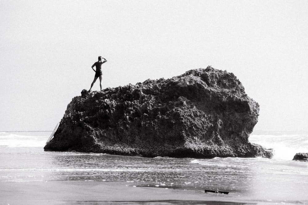 silhouette of person standing on rock formation near sea during daytime