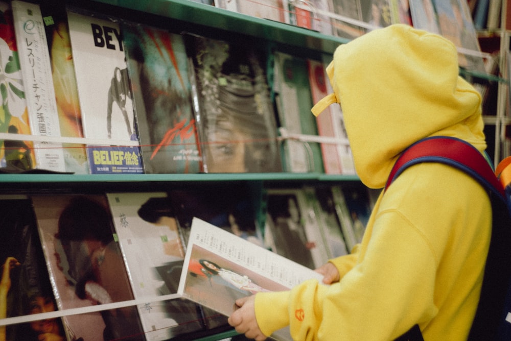 person in yellow hoodie holding white paper