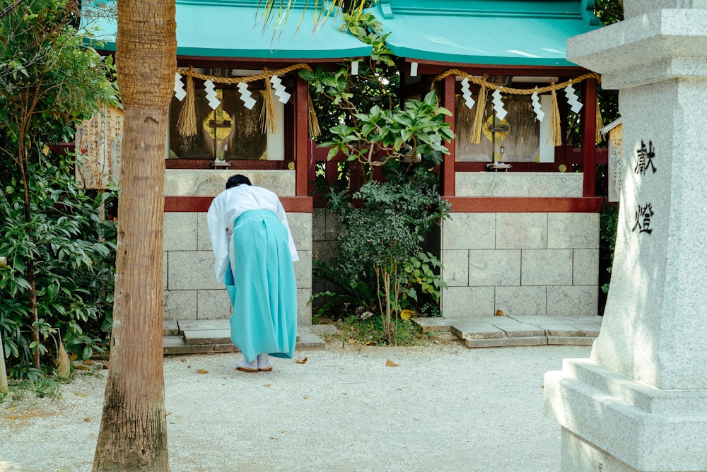 man in white thobe standing near green and white concrete building during daytime