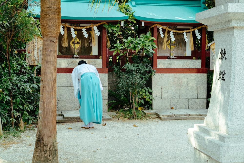 Hombre de blanco Thobe de pie cerca de un edificio de hormigón verde y blanco durante el día