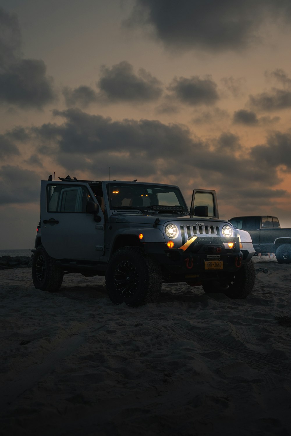 blue jeep wrangler on brown field under gray cloudy sky during daytime