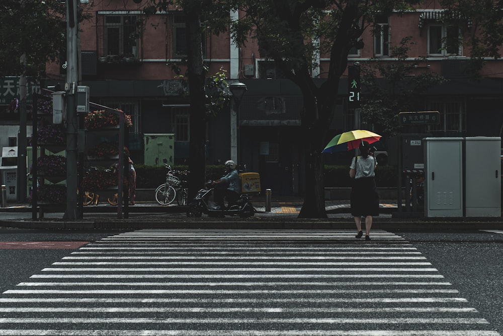 woman in black jacket holding yellow umbrella walking on pedestrian lane during daytime