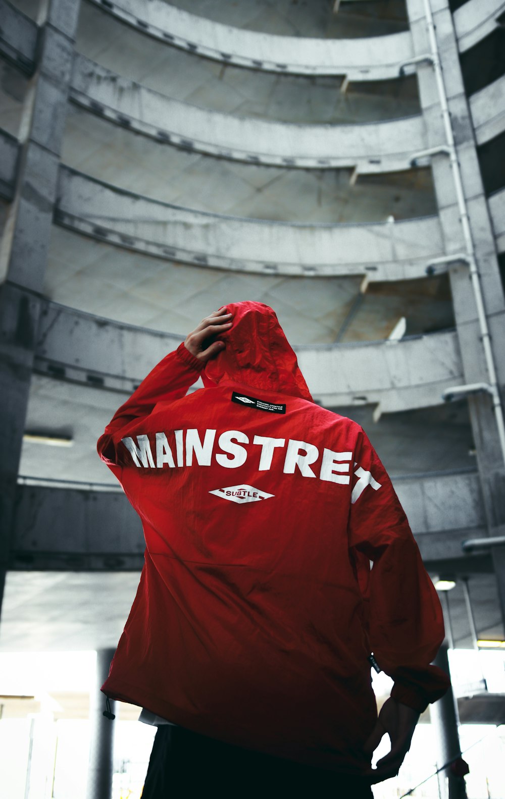 man in red hoodie standing on gray concrete floor