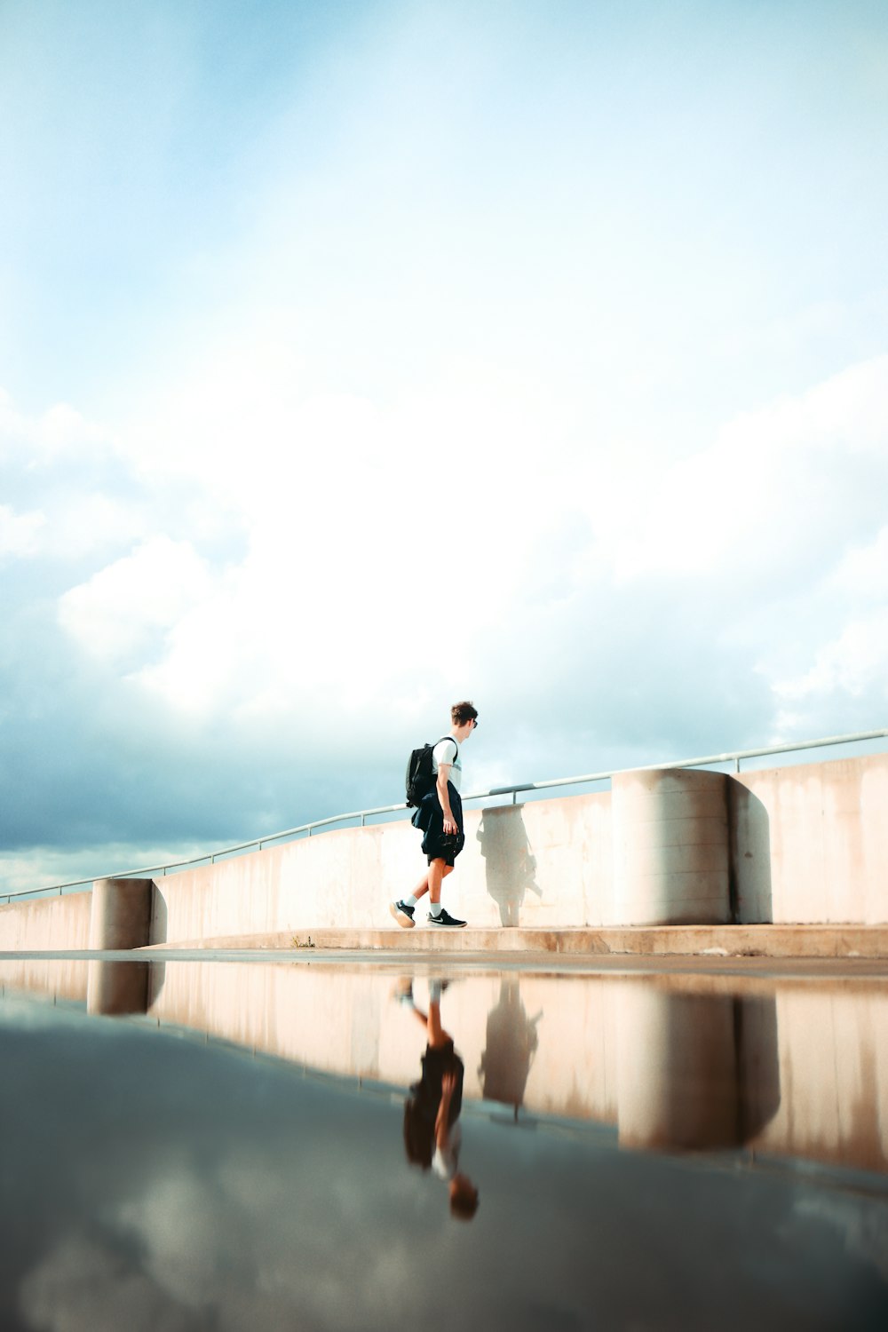 man in black jacket and pants walking on concrete bridge during daytime