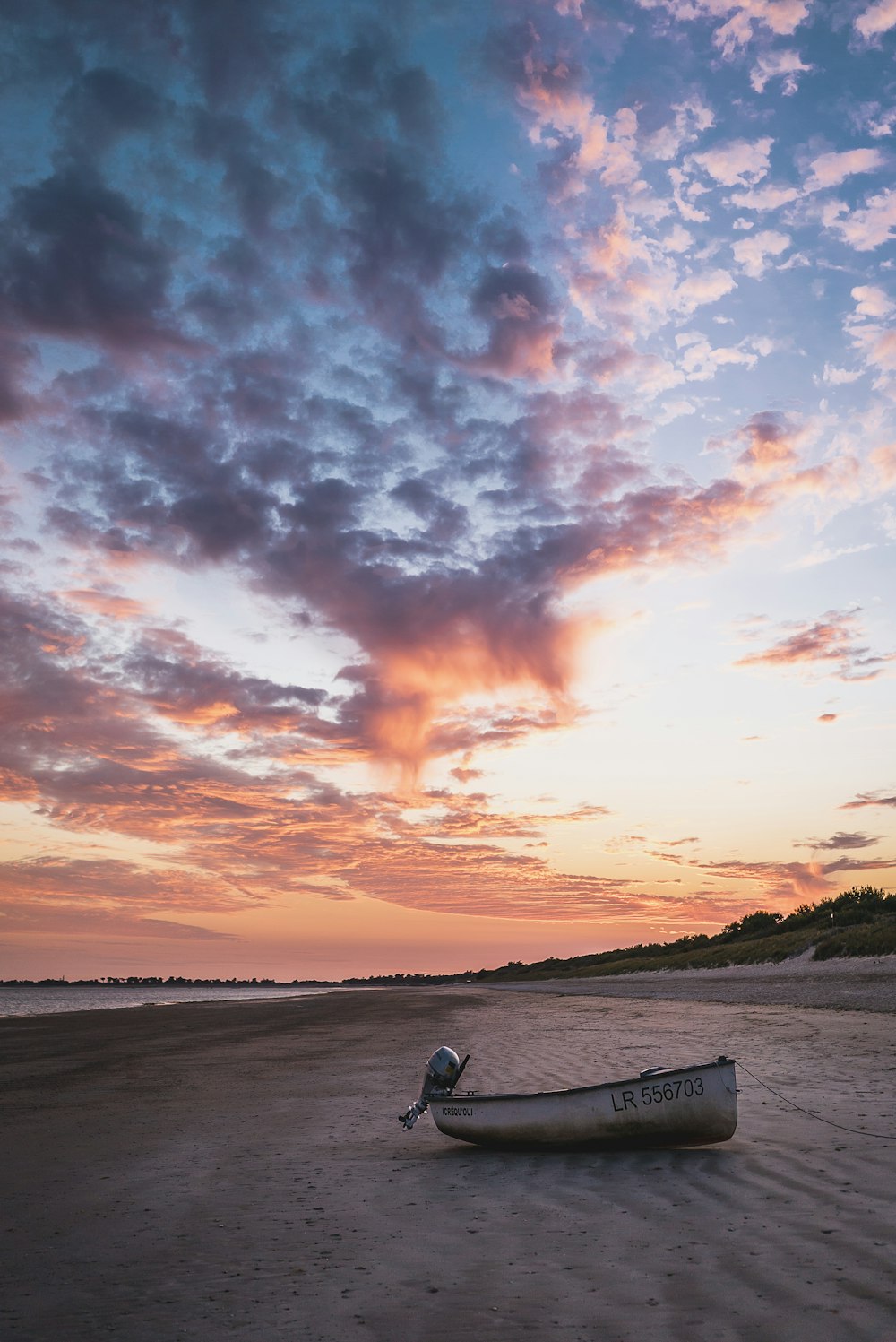 man in black jacket and black pants sitting on white wooden bench during sunset