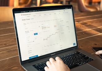 person using macbook pro on brown wooden table