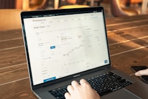 person using macbook pro on brown wooden table
