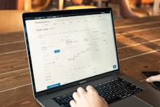 person using macbook pro on brown wooden table