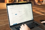 person using macbook pro on brown wooden table