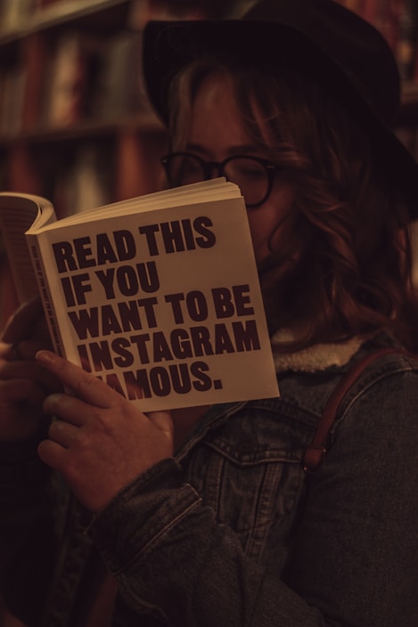 woman in blue denim jacket holding white and black book